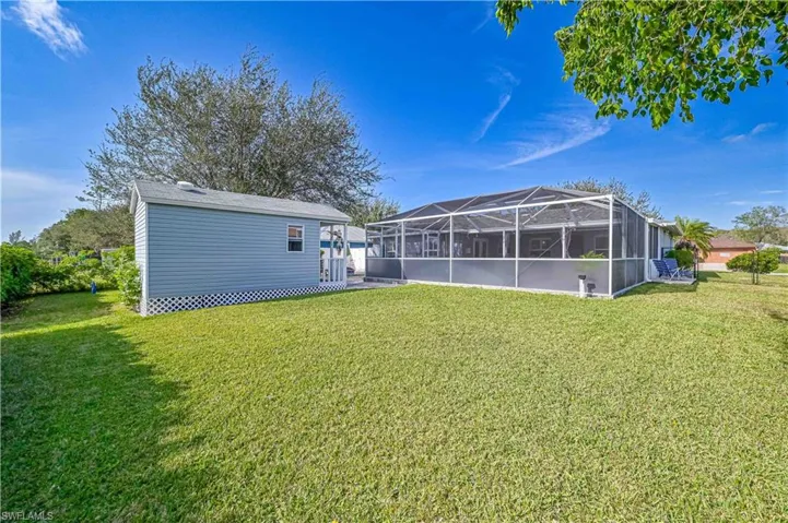 View of grassy yard with a lanai and a sunroom