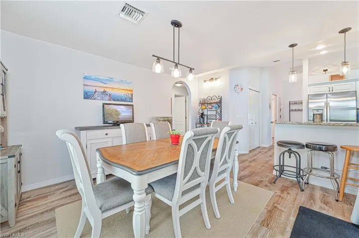 Dining room featuring arched walkways and light wood-type flooring