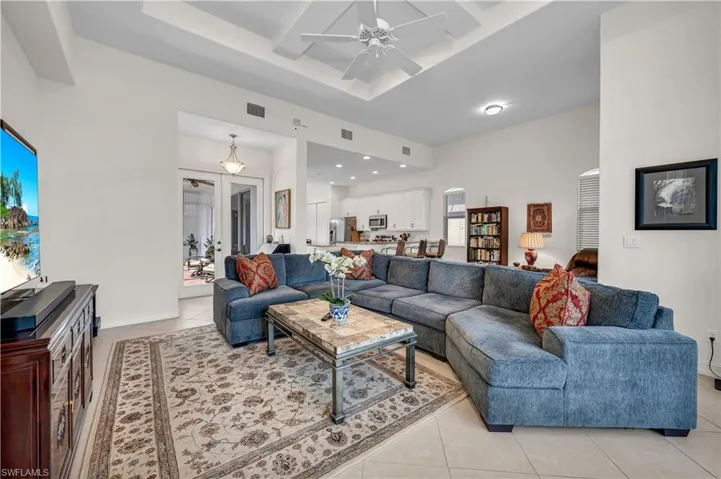 Living room featuring light tile patterned floors, visible vents, coffered ceiling, ceiling fan, and beam ceiling