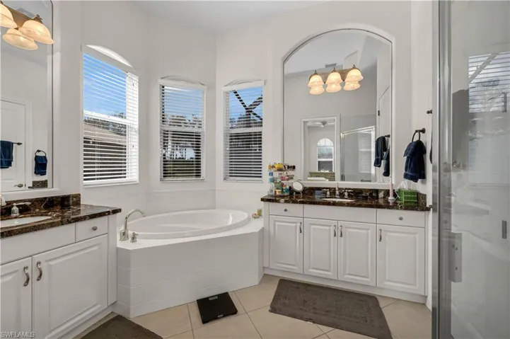 Bathroom with tile patterned flooring, a shower stall, a garden tub, and a sink