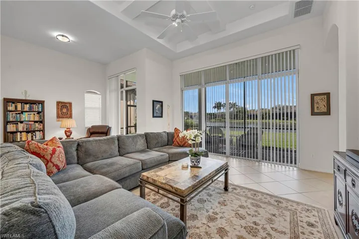 Living room featuring light tile patterned floors, arched walkways, visible vents, baseboards, and a ceiling fan