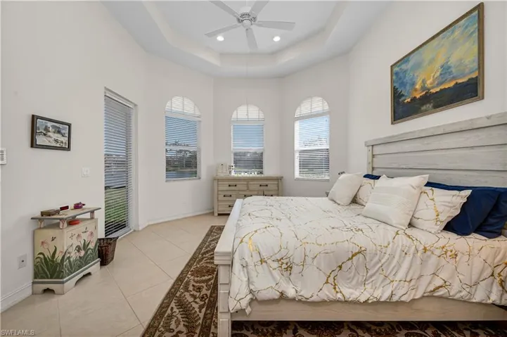 Bedroom with light tile patterned flooring, recessed lighting, a ceiling fan, baseboards, and a tray ceiling