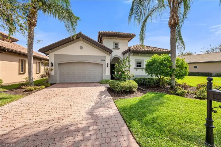 Mediterranean / spanish-style home featuring a garage, a tile roof, decorative driveway, a front lawn, and stucco siding