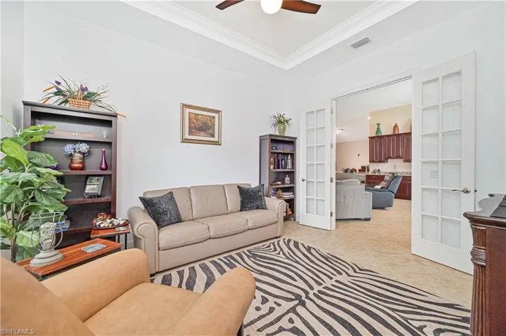 Living area featuring french doors, crown molding, light tile patterned flooring, a ceiling fan, and a tray ceiling