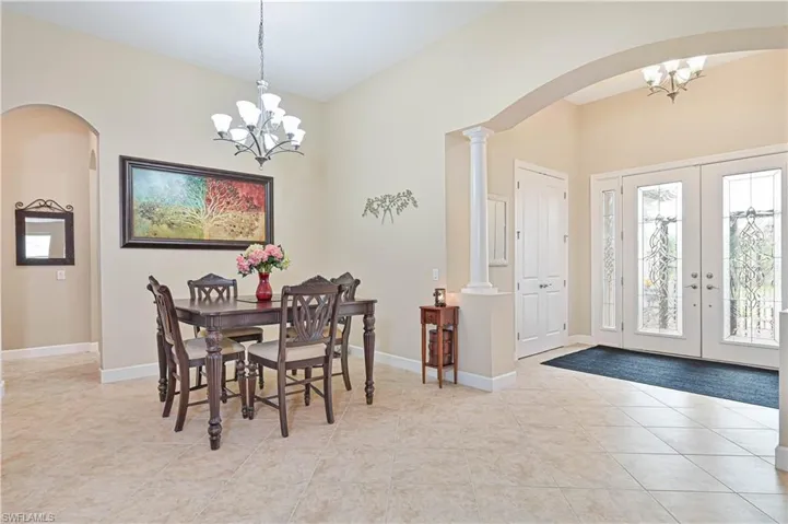 Dining area with arched walkways, a chandelier, french doors, and light tile patterned floors