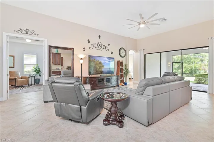 Living room with arched walkways, light tile patterned floors, and a ceiling fan