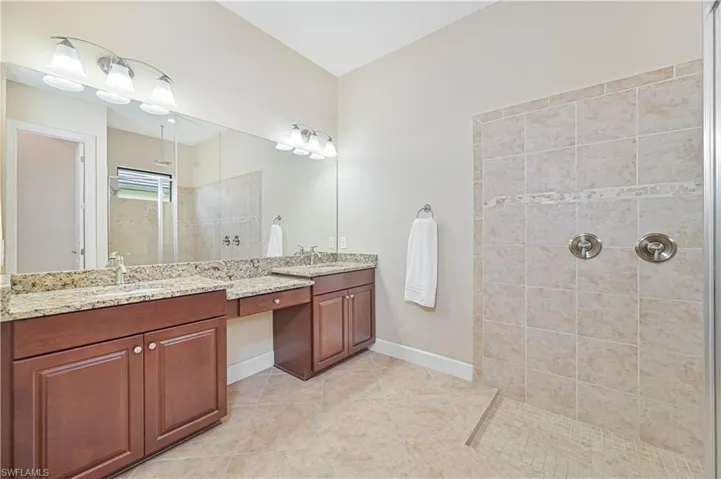 Full bath with double vanity, walk in shower, and light tile patterned flooring
