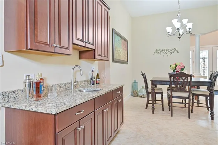 Kitchen with hanging light fixtures, light stone counters, a chandelier, and light tile patterned floors