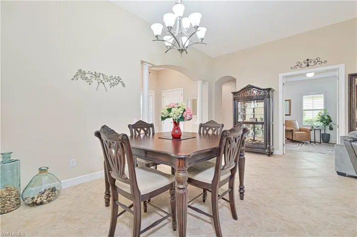Dining area featuring arched walkways, decorative columns, light tile patterned floors, and a chandelier