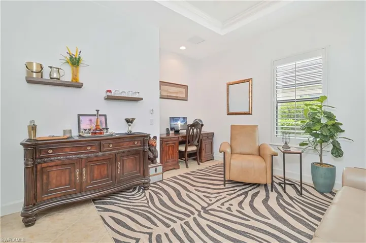 Living area featuring a desk, crown molding, a tray ceiling, light tile patterned floors, and recessed lighting