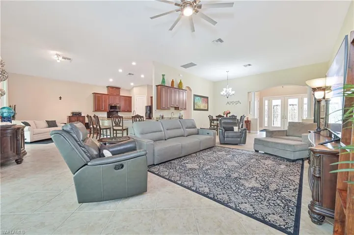 Living area with a chandelier, light tile patterned floors, a ceiling fan, french doors, and recessed lighting
