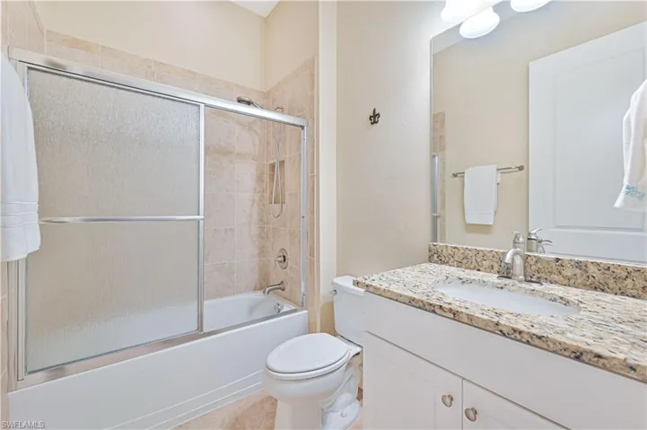 Bathroom featuring enclosed tub / shower combo, vanity, and light tile patterned floors