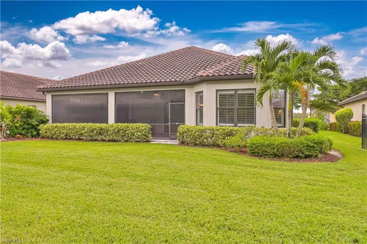 Back of property featuring a yard, stucco siding, a tiled roof, and a sunroom