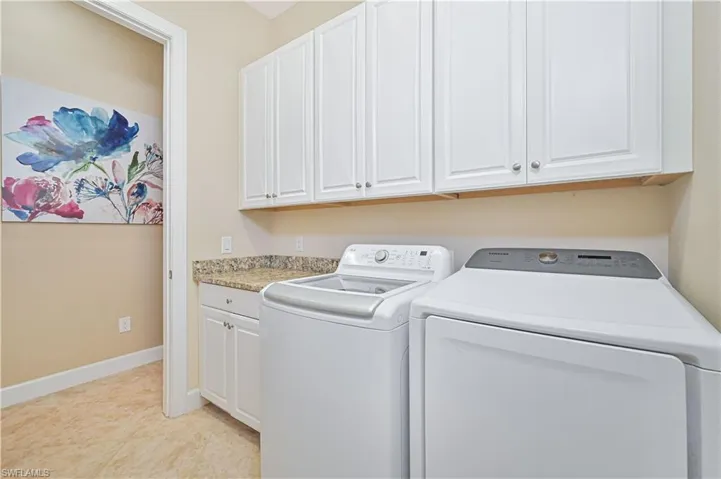 Laundry room featuring separate washer and dryer, cabinet space, and light tile patterned flooring