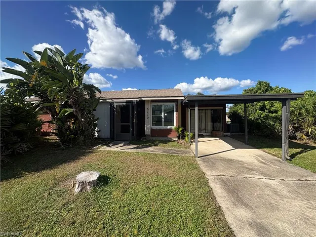 View of front facade with a front lawn, a carport, and concrete driveway