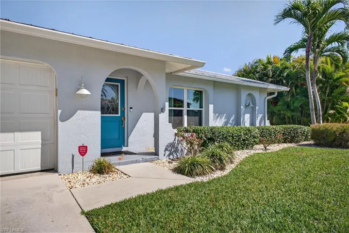 Entrance to property with a yard, stucco siding, a garage, and a porch