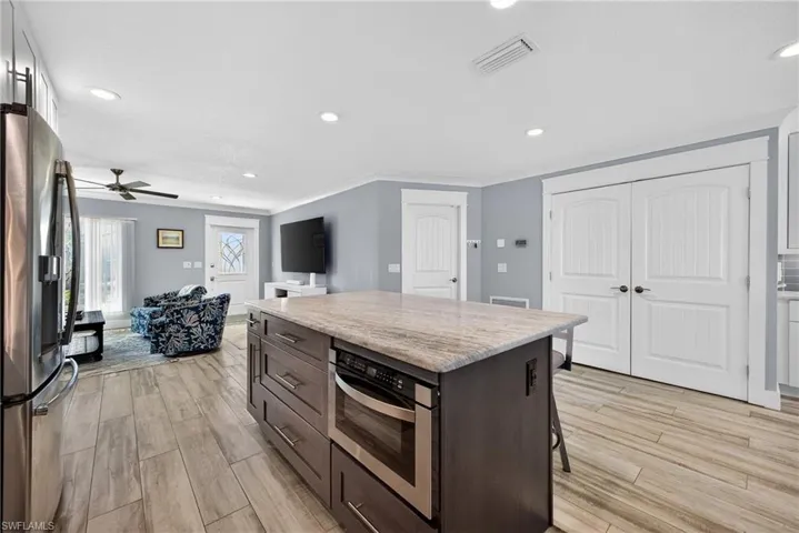 Kitchen featuring a kitchen island, stainless steel appliances, recessed lighting, ceiling fan, and a breakfast bar area