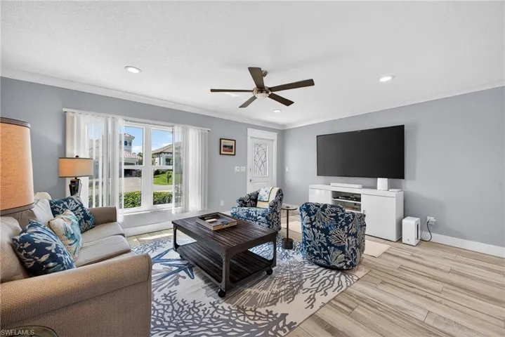 Living room with a ceiling fan, light wood-style floors, recessed lighting, and crown molding