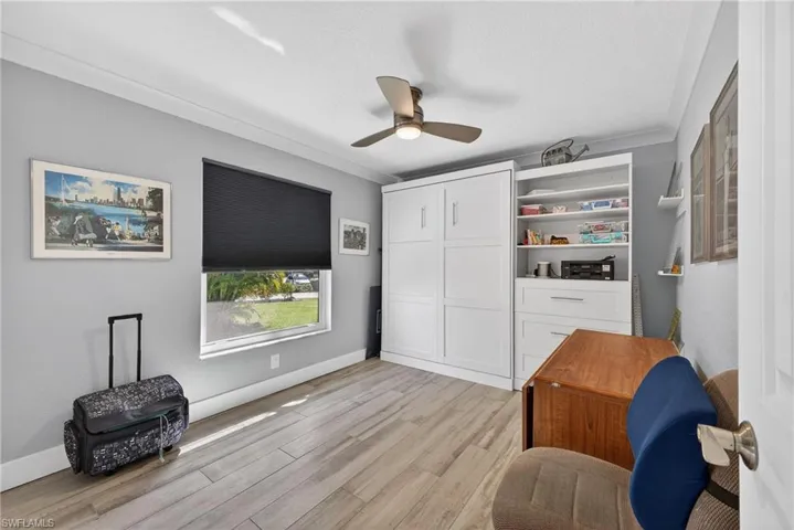 Sitting room featuring light wood-type flooring, a ceiling fan, and crown molding