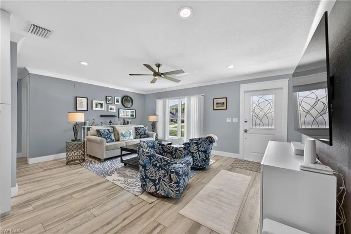Living room featuring a ceiling fan, light wood finished floors, recessed lighting, a textured ceiling, and ornamental molding