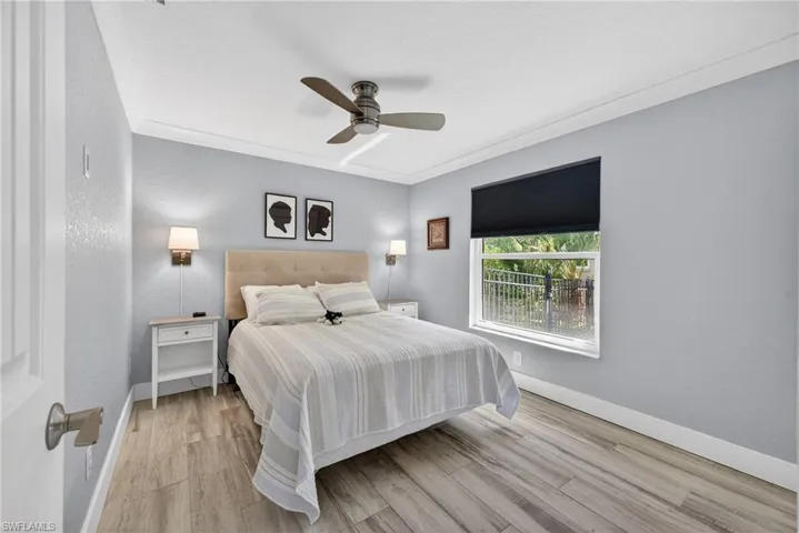 Bedroom featuring light wood finished floors, a ceiling fan, and a textured wall