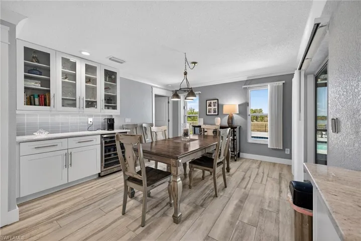Dining space with beverage cooler, a textured ceiling, and light wood-style flooring