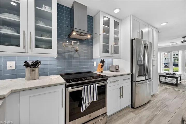 Kitchen featuring stainless steel appliances, glass insert cabinets, white cabinets, wood tiled floors, and recessed lighting