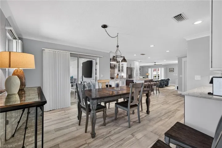 Dining room featuring ornamental molding, light wood finished floors, a textured ceiling, and recessed lighting