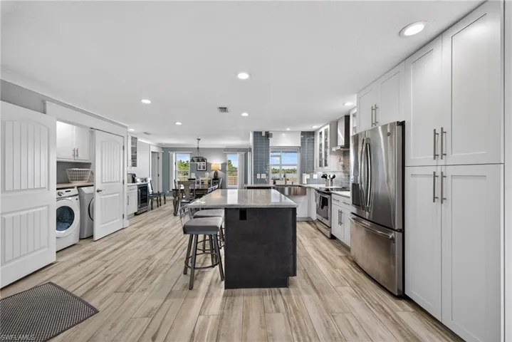 Kitchen featuring stainless steel appliances, glass fronted cabinets, a breakfast bar, pendant lighting, and dual tone cabinetry