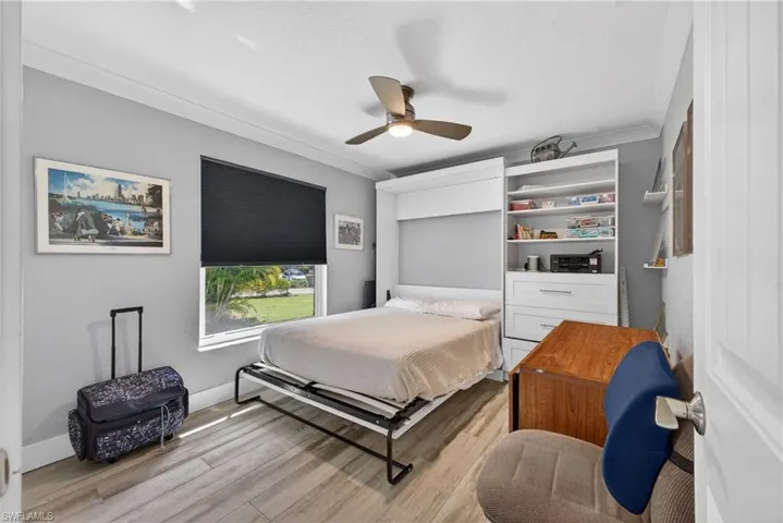 Bedroom with light wood-type flooring, a ceiling fan, ornamental molding, and a textured ceiling