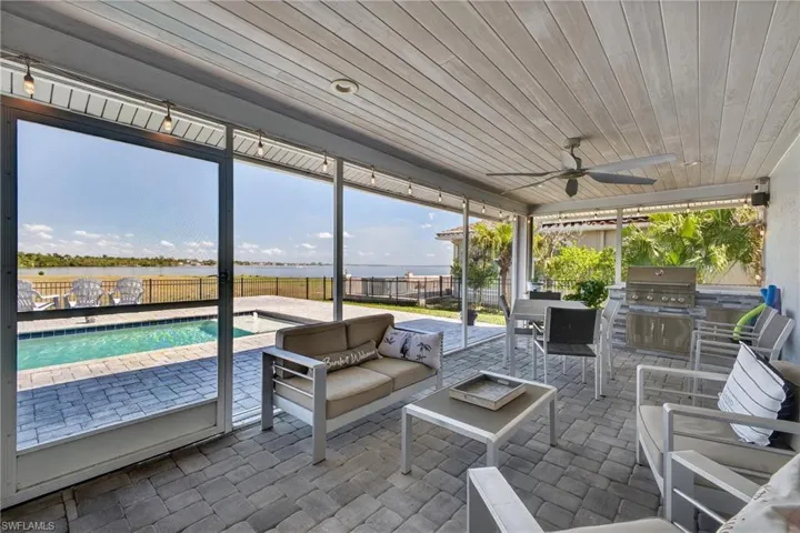 Fenced backyard featuring ceiling fan, a patio, a water view, area for grilling, and an outdoor living / dining area