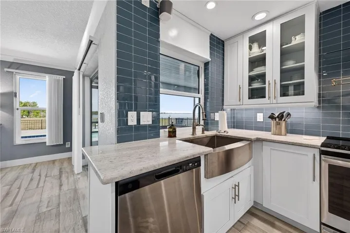 Kitchen featuring stainless steel appliances, white cabinetry, light wood-style floors, light stone countertops, and a textured ceiling