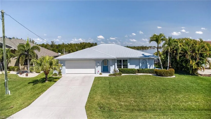Single story home featuring an attached garage, a front lawn, driveway, and stucco siding