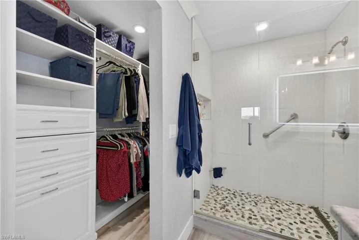 Bathroom featuring a shower stall, a walk in closet, recessed lighting, and light wood finished floors