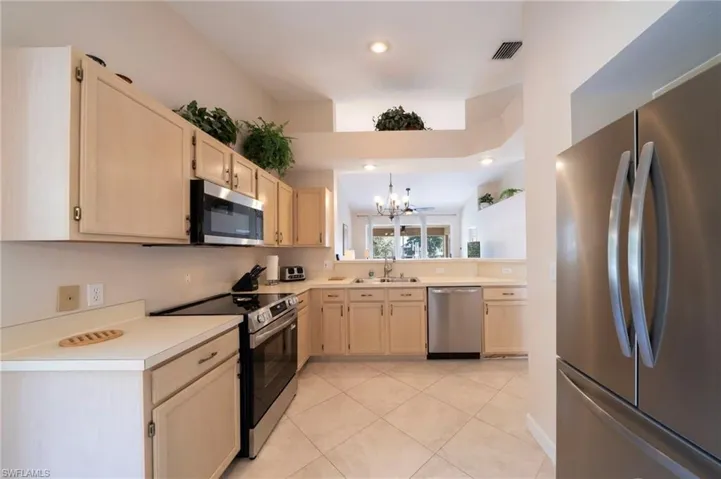 Kitchen featuring light brown cabinets, stainless steel appliances, light countertops, a chandelier, and recessed lighting