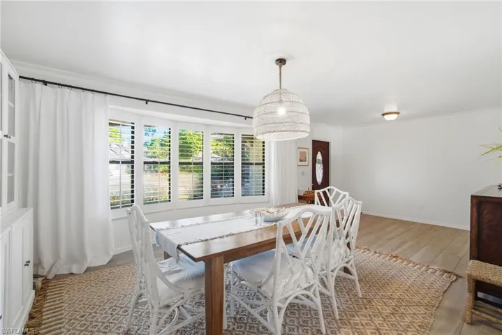 Dining space with ornamental molding and light wood-type flooring