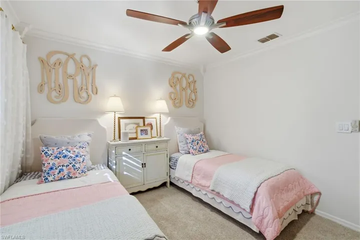 Carpeted bedroom with ornamental molding and a ceiling fan
