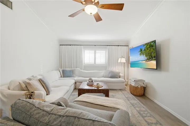 Living area featuring crown molding, wood finished floors, and a ceiling fan