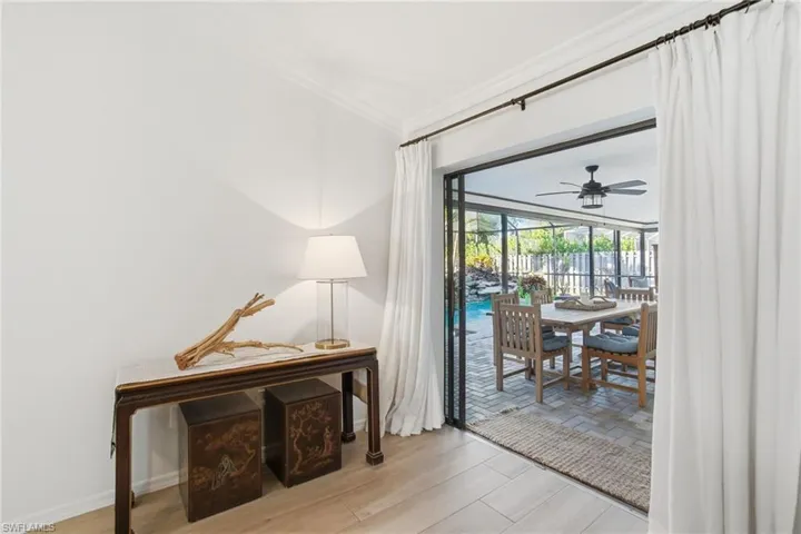 Doorway featuring ornamental molding, wood finished floors, ceiling fan, and a sunroom