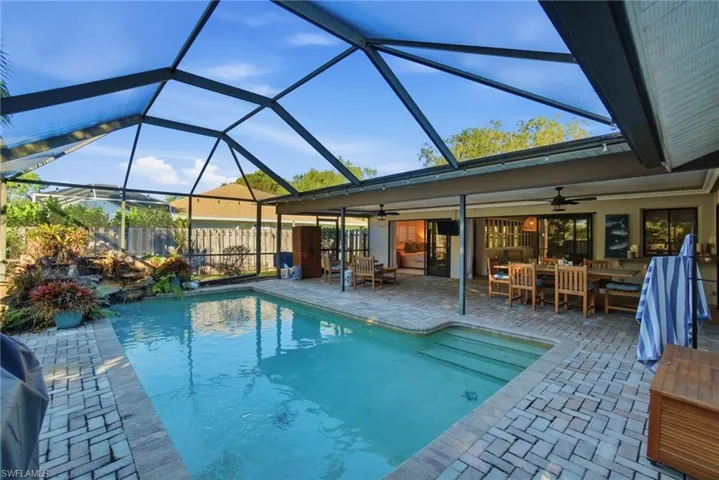 View of swimming pool with a sunroom, a patio, glass enclosure, and outdoor dining area