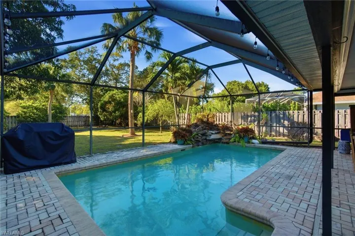 View of pool featuring a sunroom, a fenced backyard, area for grilling, a patio area, and a lanai