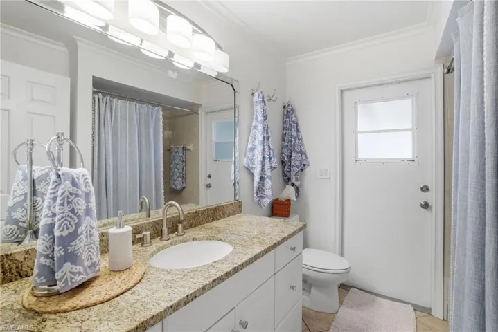 Full bathroom with crown molding, vanity, a shower with shower curtain, and healthy amount of natural light