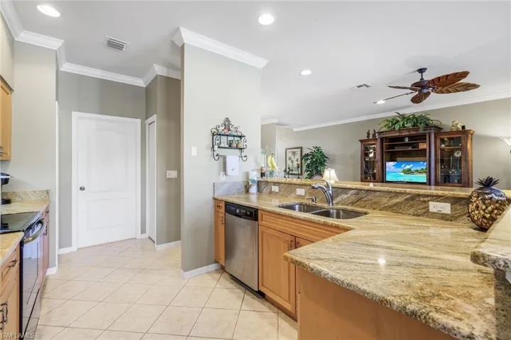 Kitchen featuring a peninsula, crown molding, light stone countertops, ceiling fan, and recessed lighting