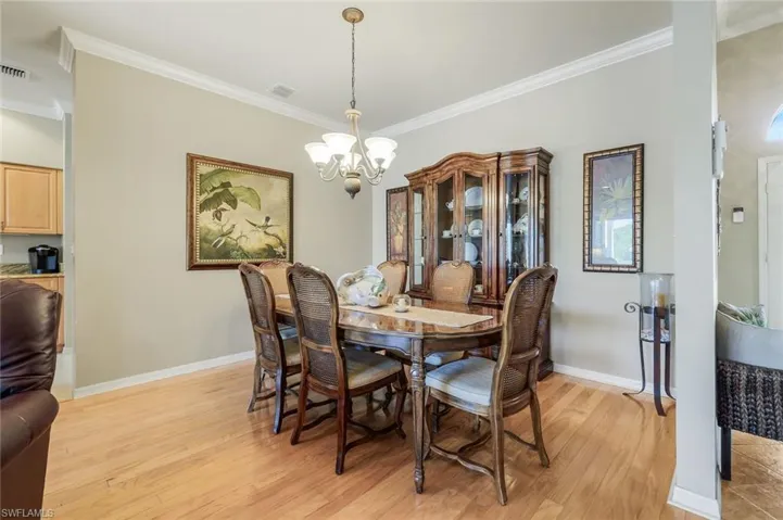 Dining room with crown molding, light wood-type flooring, and a chandelier