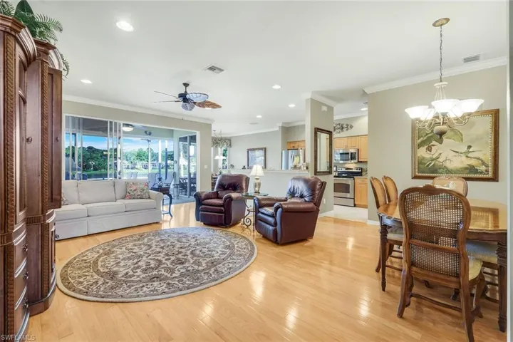Living area with a chandelier, crown molding, light wood-style flooring, a ceiling fan, and recessed lighting