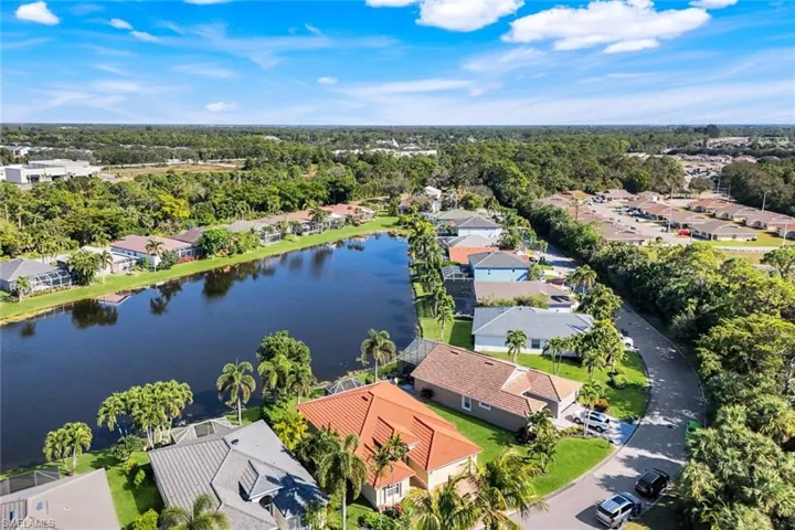 Aerial perspective of suburban area with a tree filled landscape and a nearby body of water