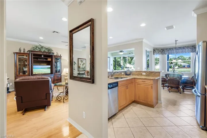 Kitchen featuring ornamental molding, stainless steel appliances, light stone countertops, hanging light fixtures, and recessed lighting
