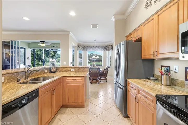 Kitchen with crown molding, appliances with stainless steel finishes, light stone counters, light tile patterned floors, and recessed lighting