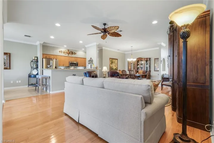 Living area featuring ornamental molding, ceiling fan, recessed lighting, light wood-type flooring, and a chandelier