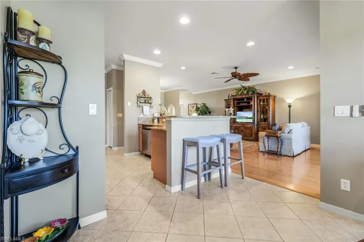 Kitchen featuring light tile patterned floors, a kitchen breakfast bar, recessed lighting, a ceiling fan, and ornamental molding